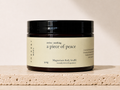 THREE & 7 Body a piece of peace Magnesium Body Soufflé 300g in a deep brown jar with black lid on beige travertine stone against an off-white studio background.