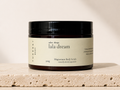 Three & 7 Body lala dream Magnesium Body Scrub 300g on beige travertine stone against an off-white studio background.